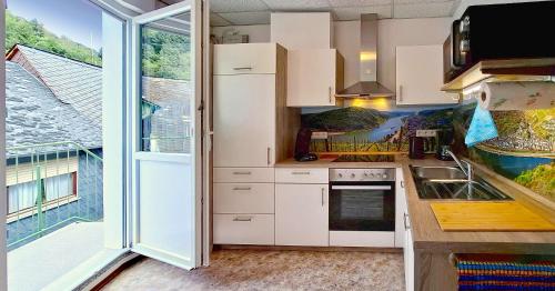 a kitchen with white cabinets and a large window at Mittelrhein-Ferienwohnung Oberwesel in Oberwesel