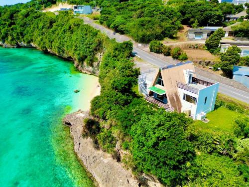 an aerial view of a house on a hill next to the water at オーシャンフロントヴィラSerenity Point37 in Nakijin