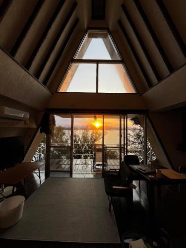 a large window in a room with a table and chairs at オーシャンフロントヴィラSerenity Point37 in Nakijin