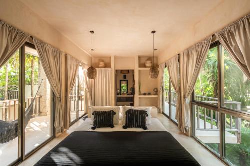 a bedroom with a large bed and large windows at NEST Tulum in Tulum