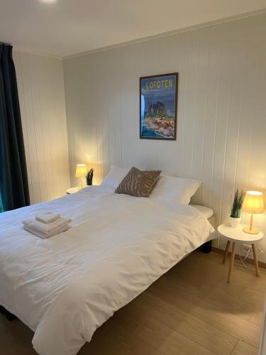 a large white bed in a room with two tables at Reine Sea Apartment in Moskenes