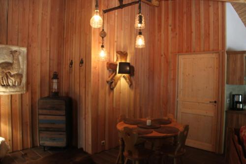 a room with a wooden wall with a table and lights at L'isba des bois, hors du temps in Janvry