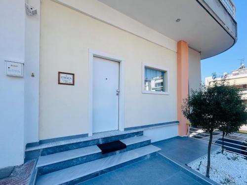 a white building with a white door and a plant at Ithaca: Διαμέρισμα με αυτόνομη είσοδο. in Thessaloniki
