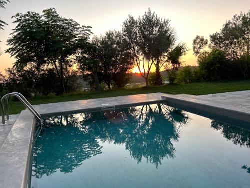 a swimming pool with a sunset in the background at Hilltop Villa in Shetaj
