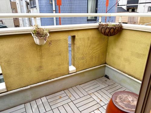 a balcony with two potted plants and a window at 覚羅中央区別荘101室 in Chiba