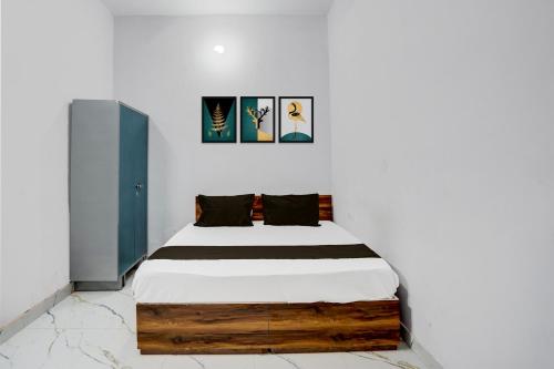 a bed in a white room with two pictures on the wall at HOTEL O VIP HILL HOMESTAY in Mājra