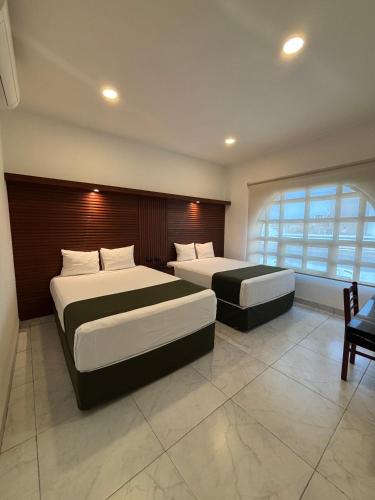 メリダにあるHotel Colonial de Meridaのベッドが2つと大きな窓がある寝室