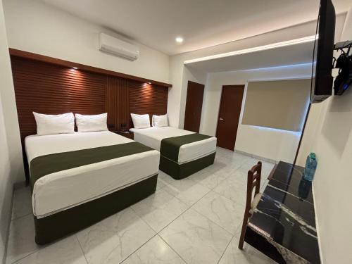 a hotel room with two beds and a flat screen tv at Hotel Colonial de Merida in Mérida
