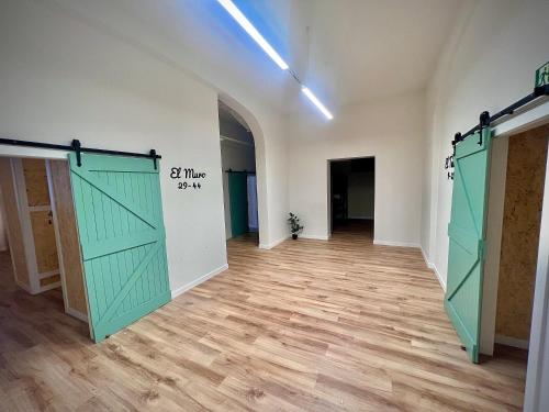 a room with two green doors and a wooden floor at Bajamar hostel in Laredo