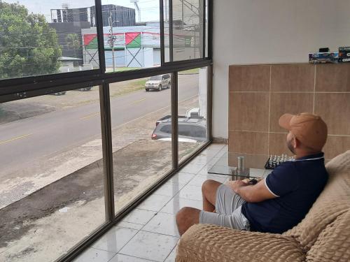 a man sitting on a couch looking out a window at Hotel Pensión Galicia in Obaldía