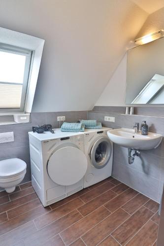 a bathroom with a washing machine and a sink at Tweethus in Langeoog