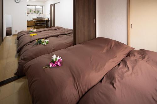 three beds in a room with flowers on them at Guest House Shine Bright - Vacation STAY 19289 in Fukuoka