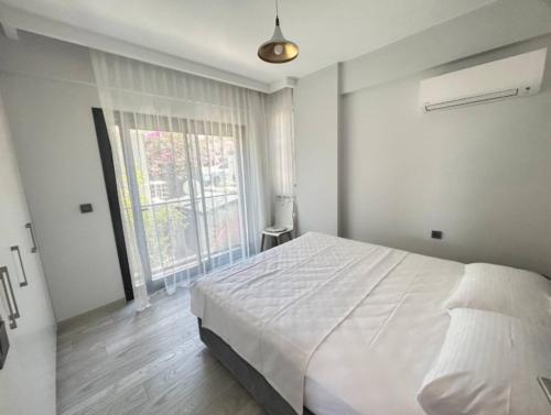 a bedroom with a white bed and a large window at Vista Marina Çeşme in Çeşme