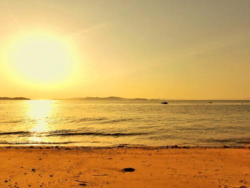 a beach with the sun setting over the ocean at NORTHSHOR Ehime 2F - Vacation STAY 12964 in Matsuyama