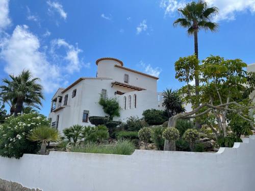 ein weißes Haus mit Palmen und einem Zaun in der Unterkunft Zen House in Benitatxell
