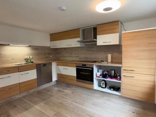 a kitchen with white and wooden cabinets and appliances at Design-Apartment im Zentrum von Scheidegg in Scheidegg