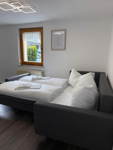 a bed with white sheets and pillows in a room at Design-Apartment im Zentrum von Scheidegg in Scheidegg