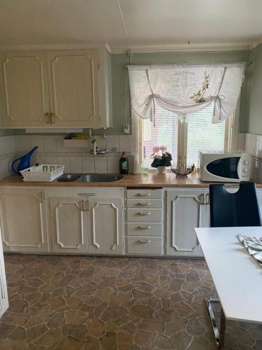 a kitchen with white cabinets and a sink and a window at Lasmarmas in Älvkarleby