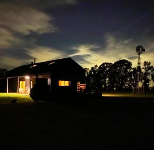 a small house with a windmill in the background at Casa de Campo Galpon San Antonio de Areco in San Antonio de Areco