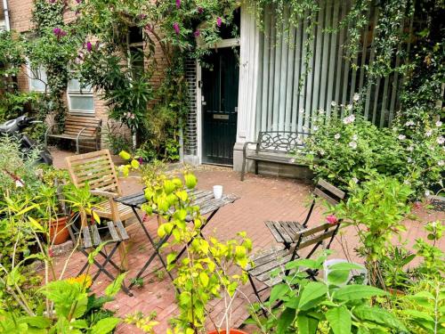 a porch with two chairs and a table and flowers at Marijke's guestroom in Amsterdam