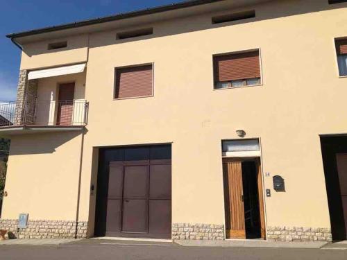 a white house with two garage doors and a balcony at Appartamento “Rosy” in Stia