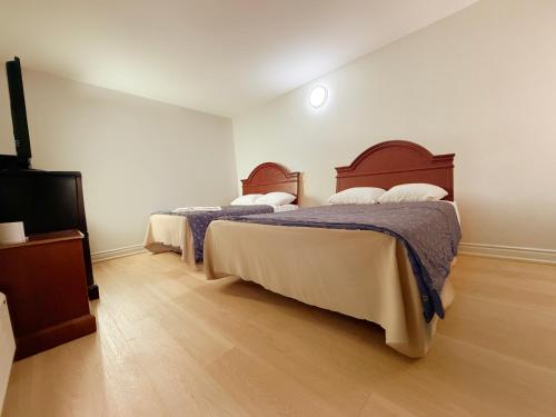 a bedroom with two beds and a flat screen tv at Idlewood Inn in Toronto
