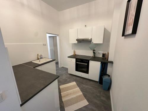 a kitchen with white cabinets and a black counter top at Pestalozzi Beach & City Apartment in Bremerhaven