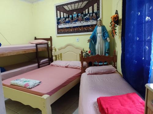 two beds in a room with a statue of a woman at Casa da Tia Lá próximo ao Santuário Nacional preço único pela casa cabem até seis pessoas in Aparecida