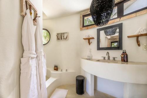 a white bathroom with a sink and a mirror at NEST Tulum in Tulum
