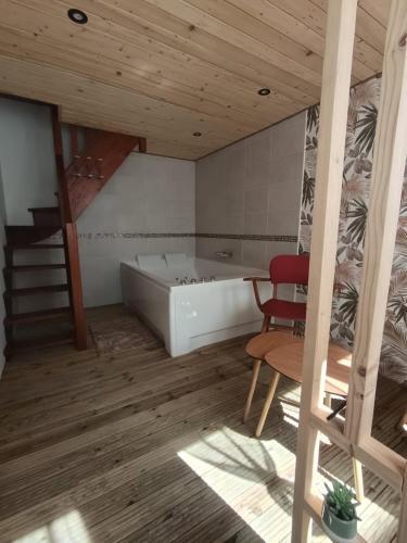 a bathroom with a tub and a table and a chair at Le rouge baiser Love room in Ault
