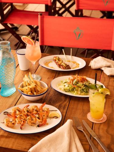 a wooden table with plates of food and drinks at Brett's Home in Harbour Island