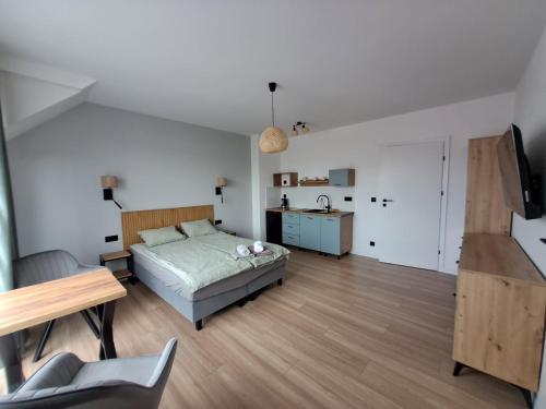 a bedroom with a bed and a table and a kitchen at Nad Zatoką pokoje z widokiem na jezioro in Ryn