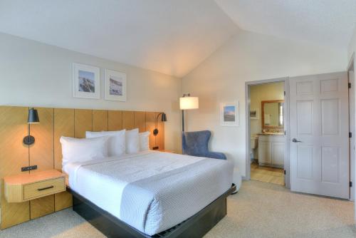 a bedroom with a white bed and a blue chair at Wedgewood Lodge in Breckenridge