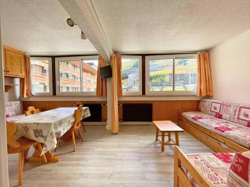 Cette chambre comprend une table, un canapé et des fenêtres. dans l'établissement Résidence Beaufortain - Studio pour 4 personnes avec vue sur la Croisette MAE-5024, aux Menuires