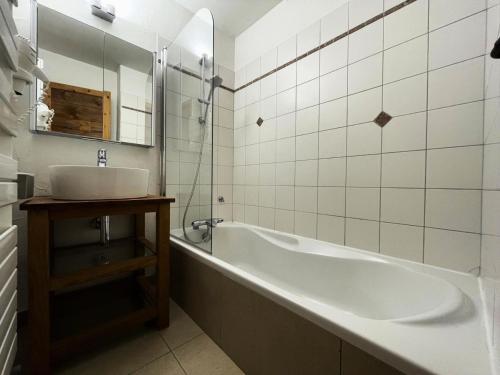 a bathroom with a tub and a sink and a mirror at Le Vieux Chalet - Chalet confortable pour 8 personnes dans le cente du village MAE-3631 in Saint-Martin-de-Belleville