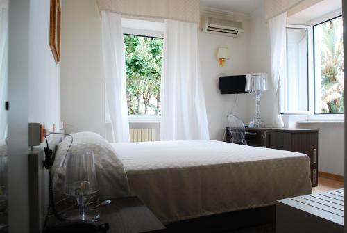a white bedroom with a bed and a window at Hotel Villa Sophia in Sanremo