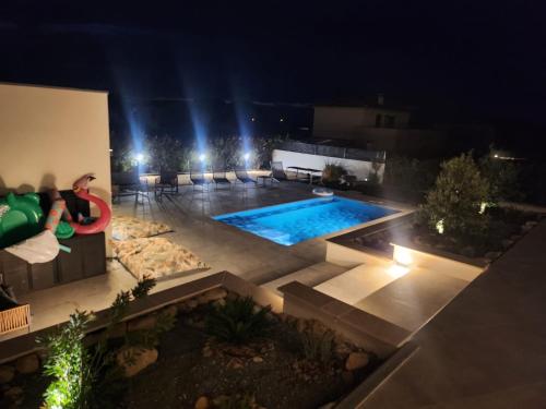 une personne assise sur un banc à côté d'une piscine la nuit dans l'établissement Villa DIMA - mer montagne piscine climatisation barbecue pétanque, à Calenzana