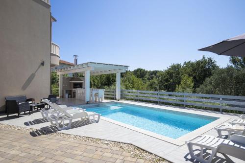 a swimming pool with chairs and a gazebo at 8-bedroom Villa Bianca with Sea View and Pool Table in Premantura