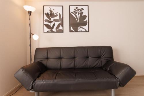 a leather couch in a living room with three pictures on the wall at LANG HOTEL Kameido - Vacation STAY 76922v in Tokyo
