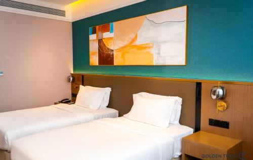 two beds in a room with a painting on the wall at Golden Tulip Kin-Oasis Kinshasa in Kinshasa
