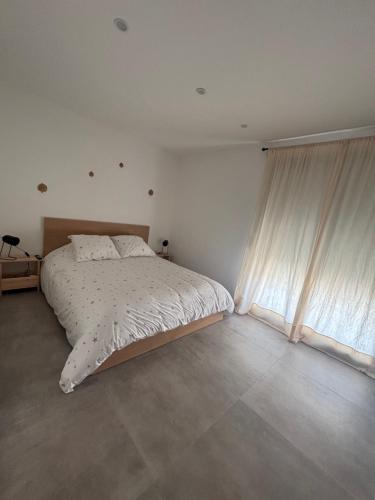 une chambre blanche avec un lit et une fenêtre dans l'établissement Villa DIMA - mer montagne piscine climatisation barbecue pétanque, à Calenzana