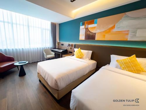 a hotel room with two beds and a desk at Golden Tulip Kin-Oasis Kinshasa in Kinshasa
