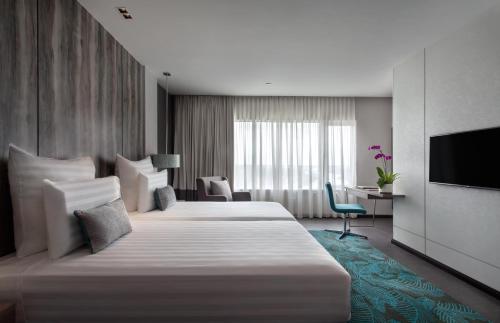 a hotel room with two beds and a television at Pullman Miri Waterfront in Miri