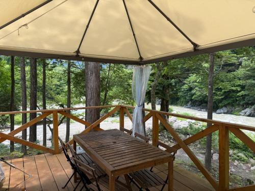 a wooden table and chairs on a porch with a tent at Riverside Glamping Nuts - Vacation STAY 78012v in Yamakami