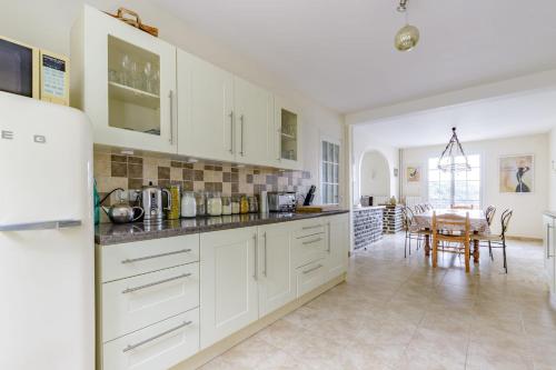 a kitchen with white cabinets and a dining room at La Pause au Bord du Lac - Ponton privé - Baignade depuis le Ponton in Cuzion