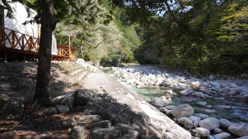 a river with rocks and a bridge in the background at Riverside Glamping Nuts - Vacation STAY 74060v in Yamakami