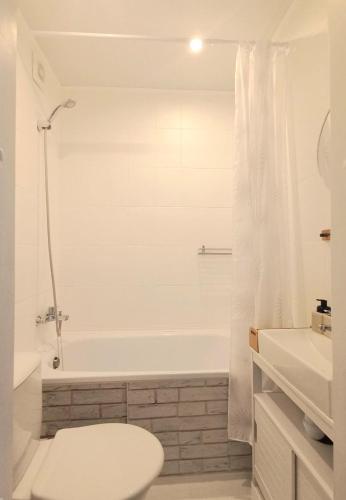 a white bathroom with a toilet and a bath tub at Narva Vibe Apartment in Narva