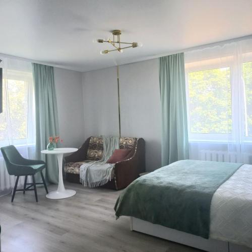 a bedroom with a bed and a chair and a table at Narva Vibe Apartment in Narva