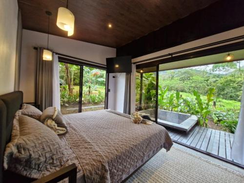 a bedroom with a large bed and a large window at Pantala Villa in Fortuna