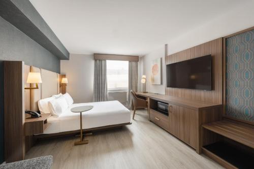 a hotel room with a bed and a flat screen tv at Holiday Inn & Suites Winnipeg Downtown by IHG in Winnipeg